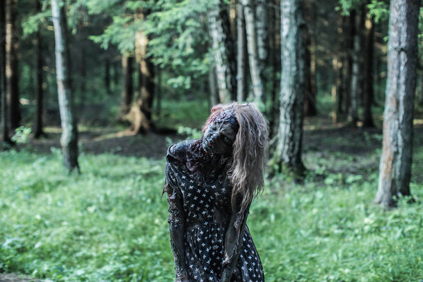 Scary zombie woman posing at forest path - 写真・画像