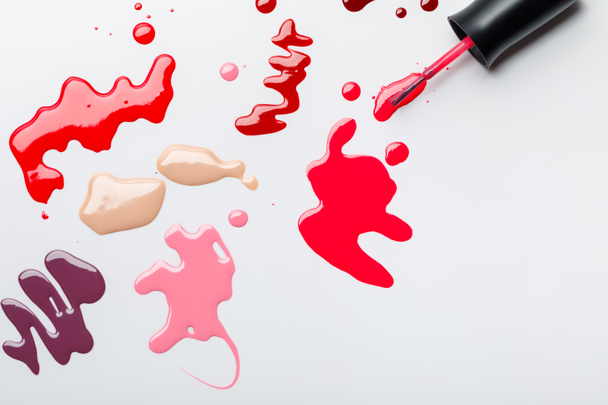 top view of wet brush near colorful spills of nail polish isolated on grey - Photo, Image