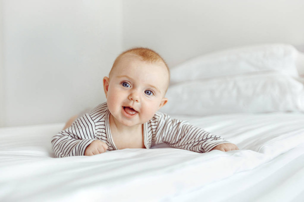 Charming happy baby on white bed - Foto, Imagem