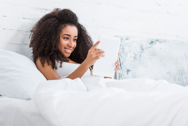 krásná africká americká žena pomocí digitálních tabletu v posteli doma - Fotografie, Obrázek
