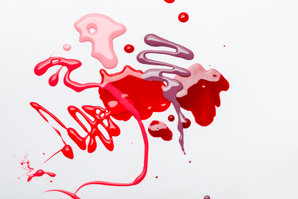 vista superior de abstracto derramado rojo y rosa gotas de esmalte de uñas aislado en gris
 - Foto, imagen