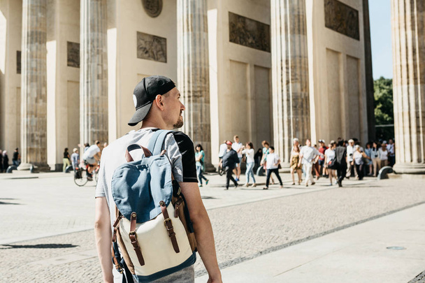 Een toerist of een student met een rugzak in de buurt van de Brandenburger Tor in Berlijn in Duitsland, kijkt naar de bezienswaardigheden. - Foto, afbeelding