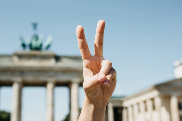La ragazza mostra un segno di pace sullo sfondo della Porta di Brandeburgo a Berlino
 - Foto, immagini
