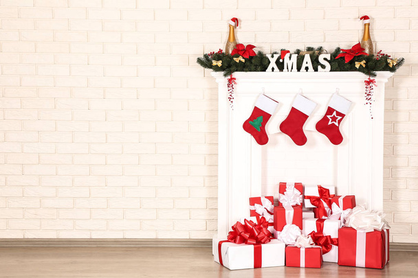 Christmas decorations with fireplace and gift boxes on brick wall background - Foto, Bild