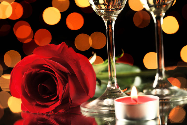 Red rose with glasses and candle on lights background - Fotó, kép