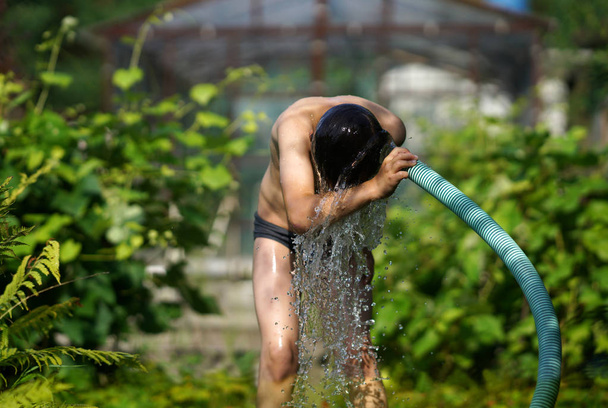 The boy with splash water in hot summer day outdoors - Foto, imagen