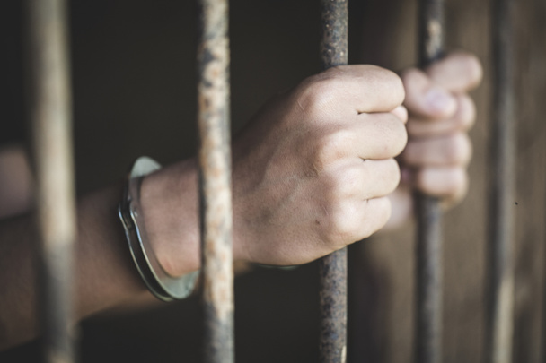 Ένας κρατούμενος πιάσει ένα ατσάλινο κλουβί σε ένα κελί, των κρατουμένων και αστυνομία έννοια - Φωτογραφία, εικόνα