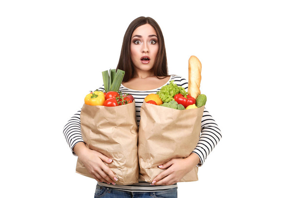 Beautiful woman holding grocery shopping bags on white background - Foto, Imagen