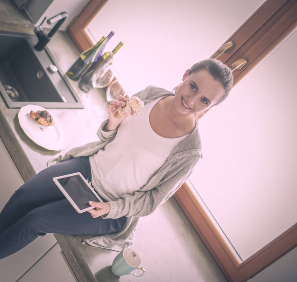 Beautiful young woman using a digital tablet in the kitchen - Foto, immagini