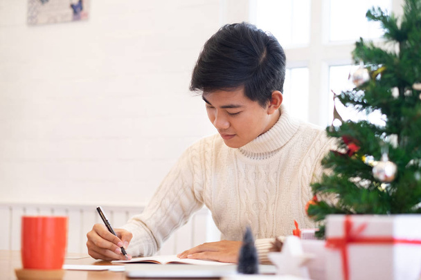 Muž psaní pohlednice doma během Vánoc a nového roku. - Fotografie, Obrázek