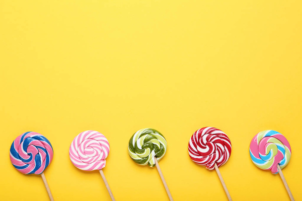 Colorful lollipops on yellow background - 写真・画像