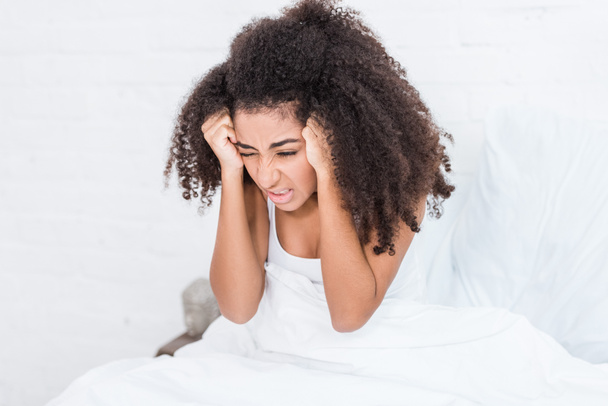 foco seletivo de jovem afro-americana tendo dor de cabeça na cama em casa
 - Foto, Imagem