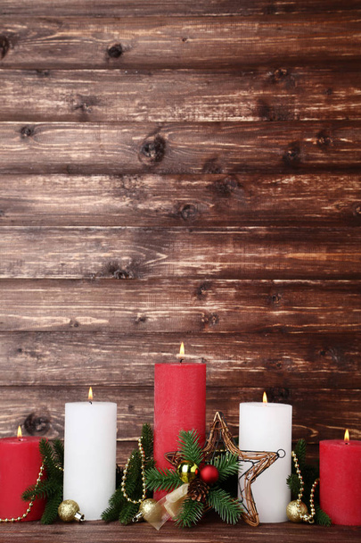 Christmas candles with fir tree branches and baubles on brown background - Photo, image