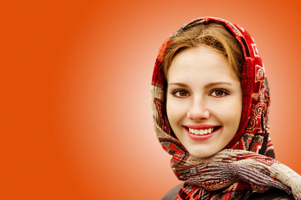 Portrait of smiling charming young woman in headscarf isolated on orange background. - Foto, Imagem