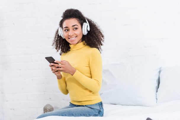 mulher africana americana em fones de ouvido ouvir música com smartphone em casa
 - Foto, Imagem