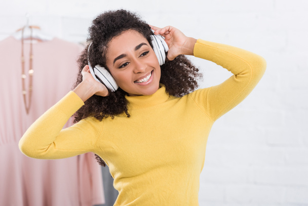 Glückliche junge Afroamerikanerin hört Musik über Kopfhörer - Foto, Bild