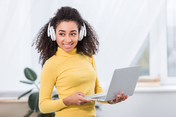 african american female freelancer in headphones working on laptop at home office  - 写真・画像