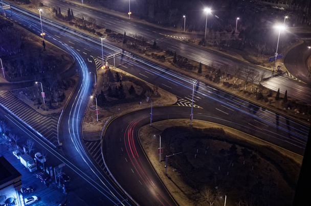 Scène van verlichte motorway kruising bij nacht met blauwe en rode lichte gebruikssporen. Deze scène werd genomen in Shenyang, China - Foto, afbeelding