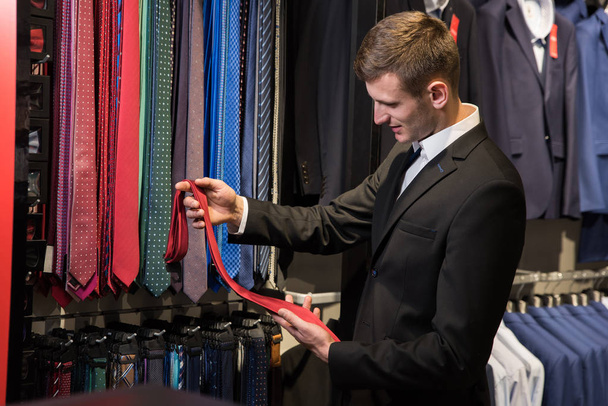 Man in male clothes shop choosing tie  - Foto, Bild