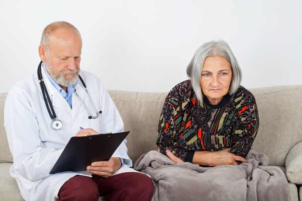 Врач с планшетом диагностирует пожилых пациентов дома
 - Фото, изображение