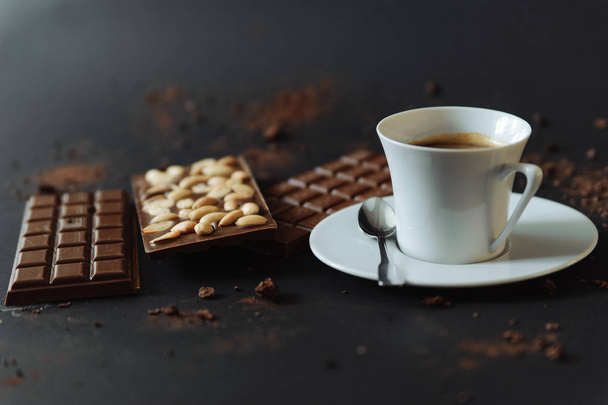 Nahaufnahme der Tasse mit Kaffee und Vollmilchschokolade mit Nüssen   - Foto, Bild