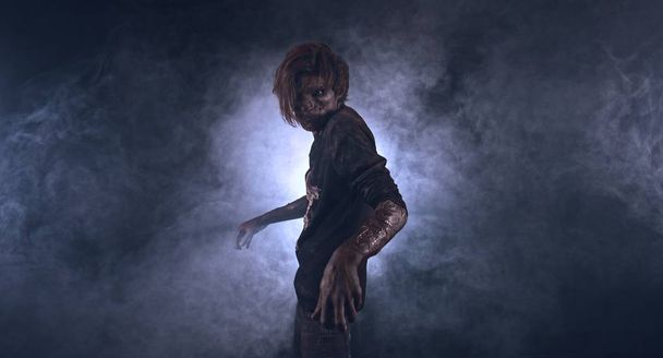 Scary zombie man posing against dark misty background with backlight - Fotografie, Obrázek