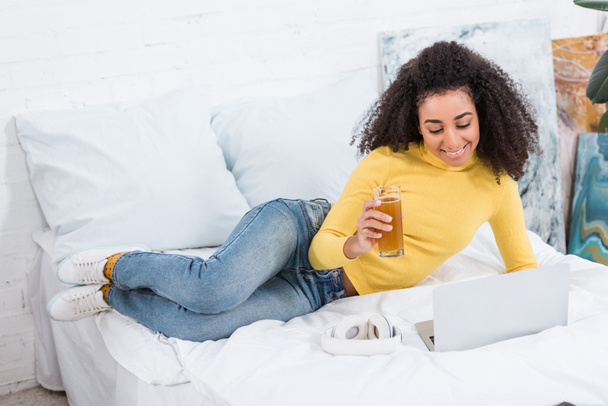 freelance femminile con vetro di succo fresco che lavora su computer portatile in letto a casa
 - Foto, immagini
