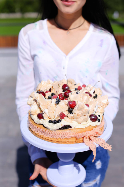 Девушка в белой блузке держит торт на день рождения
. - Фото, изображение