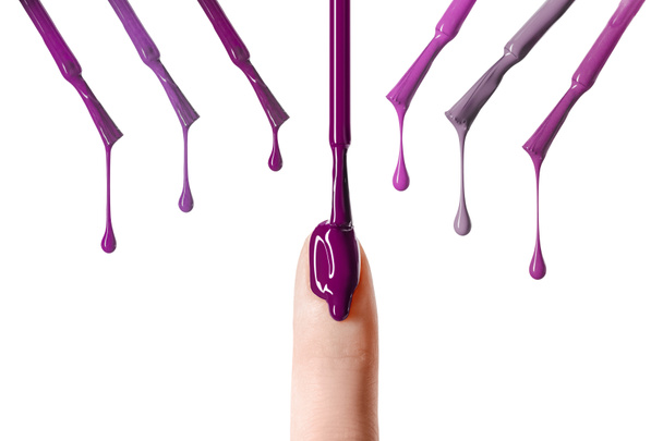 messy drop of purple nail polish dripping on nail isolated on white  - Fotó, kép