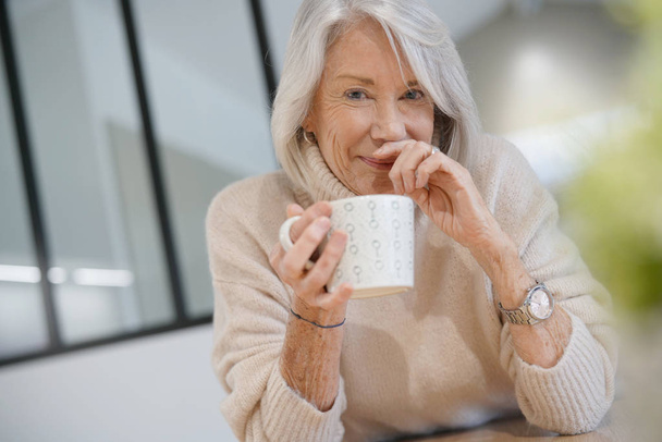  Senior woman at home with hot drink                               - Foto, Imagem