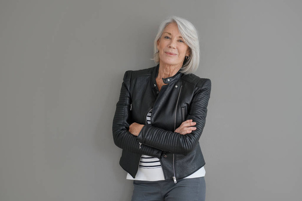  Modern senior woman in leather jacket on isolated grey background                               - Фото, изображение