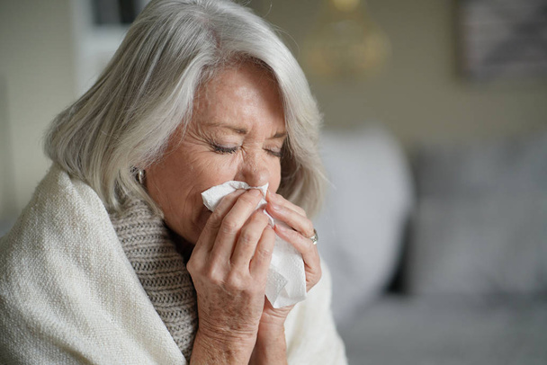   Senior woman blowing nose and feeling unwell                            - Foto, Bild