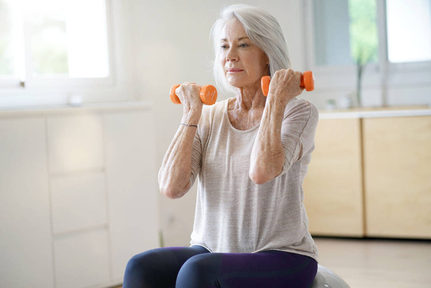  Attractive elderly woman exercising at home with swiss ball                               - Foto, immagini