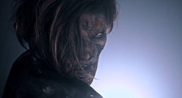 Scary zombie man posing against dark misty background with backlight - Фото, зображення