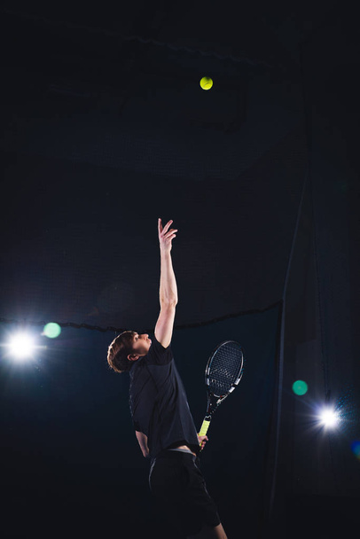 A man is playing tennis. A man in a red T-shirt beats a tennis ball. - Fotografie, Obrázek