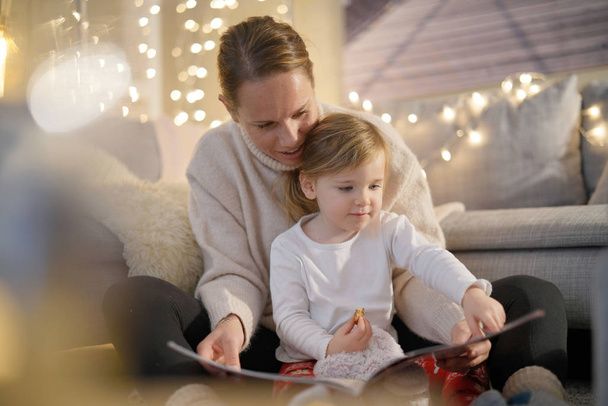  Przytulne, matka i córka czytaniu opowieść w domu                              - Zdjęcie, obraz