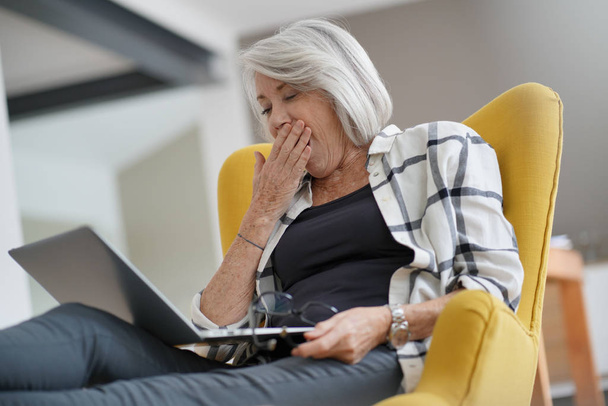  Stylish senior woman yawning at computer                        - Foto, Bild