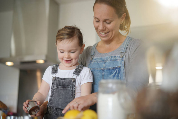   Mother and daughter baking at home                              - Foto, Bild