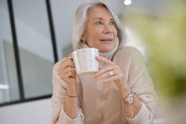  Senior woman at home with hot drink                               - Foto, Imagem