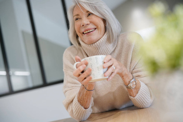  Seniorin zu Hause mit Heißgetränk                               - Foto, Bild