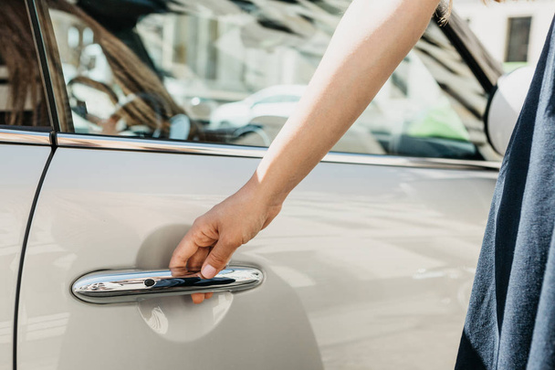Крупный план на женской руке открывает дверь нового современного автомобиля
 - Фото, изображение