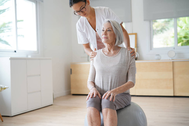 Senior woman exercising with her physiotherapist and swiss ball                               - Φωτογραφία, εικόνα