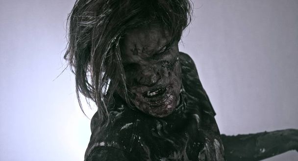 Strašidelný zombie muž vystupují proti temné zamlžené pozadí s podsvícením - Fotografie, Obrázek