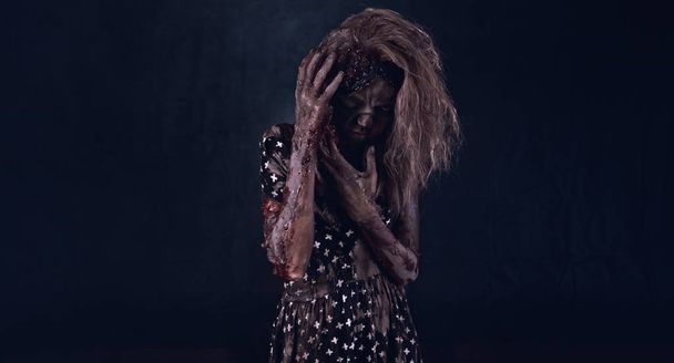Creepy zombie woman posing against dark background - Foto, Bild