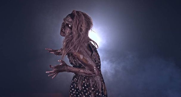 Creepy zombie woman posing against dark background - Foto, Imagen