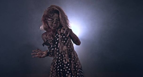 Creepy zombie woman posing against dark background - Фото, изображение