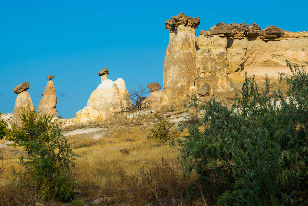 The rocks are shaped like mushrooms. Fairy chimneys view near Cavusin Town in Cappadocia, Anatolia, Turkey. Popular Turkish mountains for tourists, the symbol of Kapadokya. - Foto, Imagem