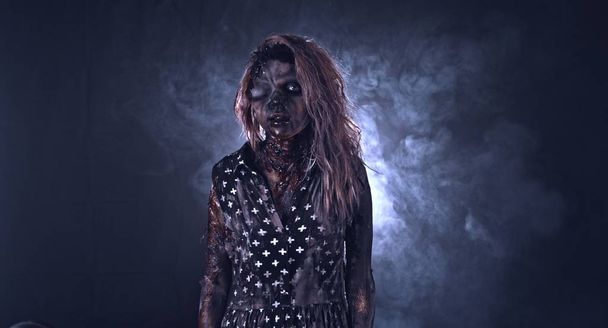 Creepy zombie woman gesturing against dark misty background - Fotó, kép