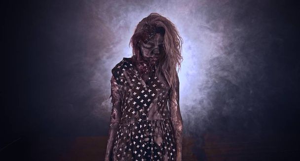 Scary zombie woman posing against dark background with backlight - Fotó, kép