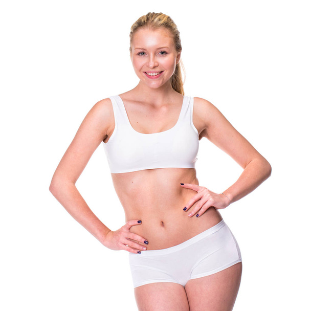 Portrait of a young blonde woman in sportswear without makeup. Sexy beautiful model in white fitness clothing, isolated on white background - Photo, Image